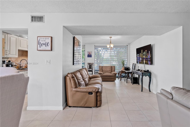 living room with a textured ceiling, an inviting chandelier, and light tile patterned floors