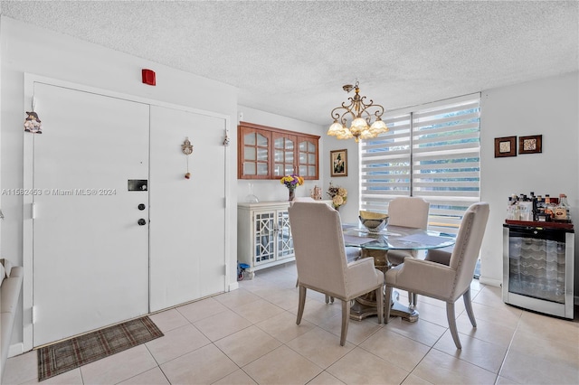 dining room with light tile patterned floors, an inviting chandelier, wine cooler, and a textured ceiling