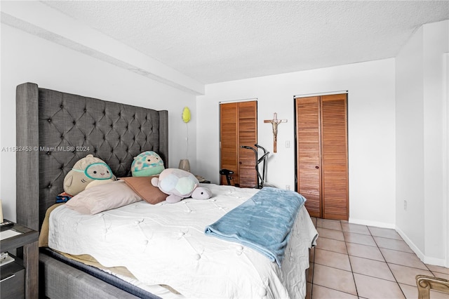 tiled bedroom with a textured ceiling and two closets