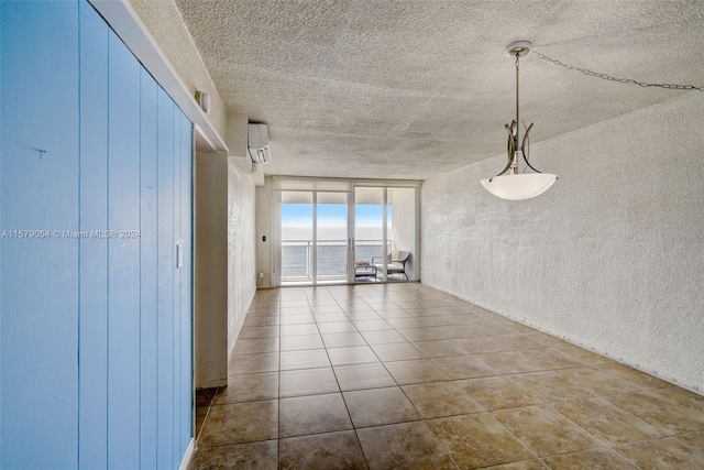 empty room featuring an AC wall unit, tile flooring, and a textured ceiling