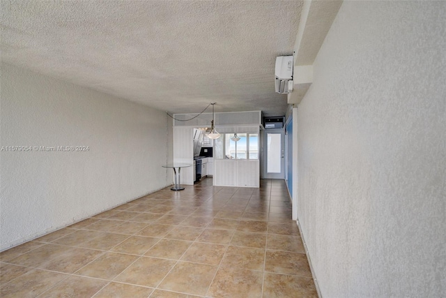 unfurnished living room featuring an AC wall unit, tile flooring, and a textured ceiling