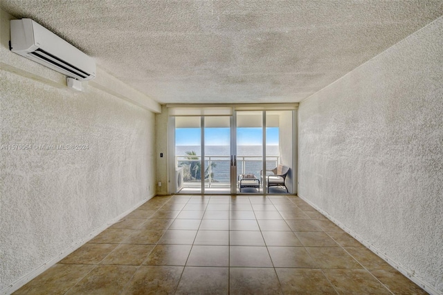 tiled spare room featuring a textured ceiling, expansive windows, a water view, and a wall mounted air conditioner