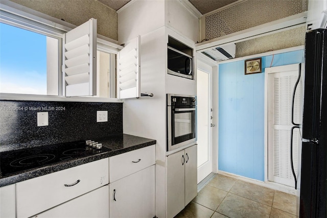 kitchen featuring black appliances, white cabinets, tasteful backsplash, and light tile floors