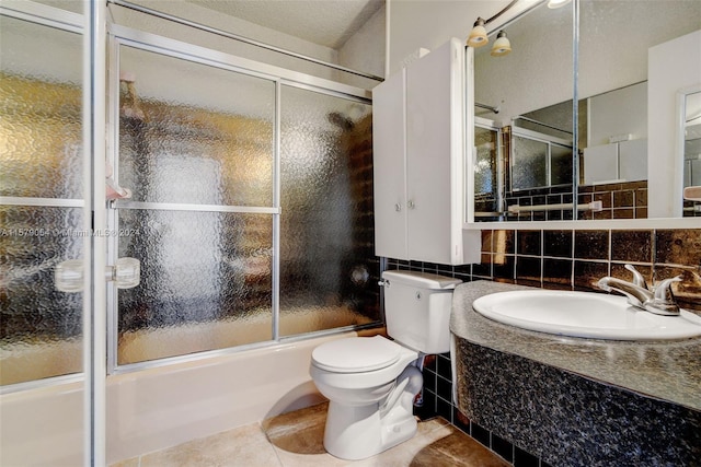 full bathroom featuring tile flooring, tile walls, shower / bath combination with glass door, toilet, and vanity