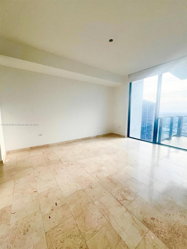 spare room featuring tile patterned flooring and a wall of windows