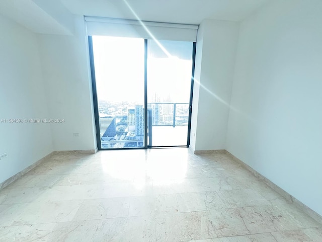 empty room featuring a wall of windows and light tile patterned floors