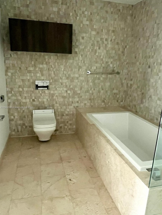 bathroom with tile patterned floors, toilet, and tiled bath