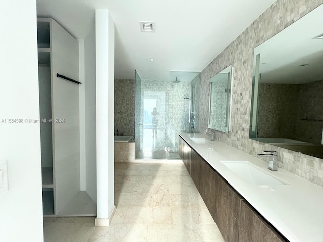 bathroom with double vanity, decorative backsplash, tile walls, tiled shower, and tile patterned floors