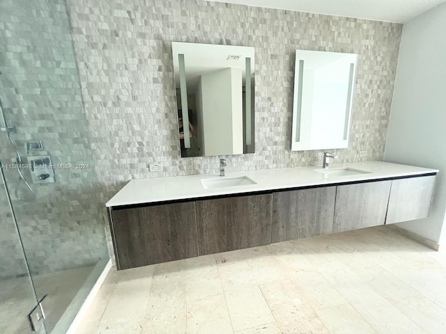 bathroom with double sink vanity, a tile shower, and tile patterned flooring