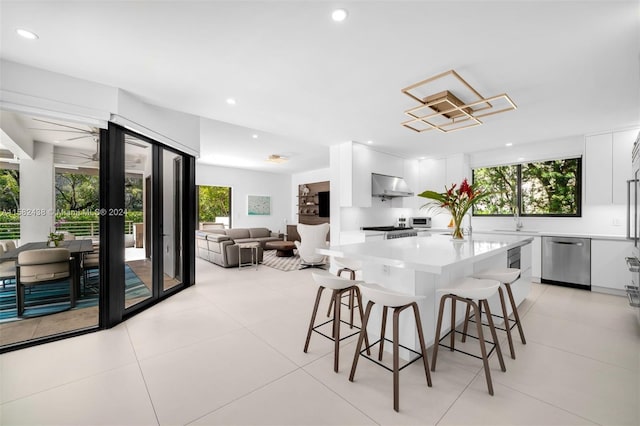 kitchen with white cabinets, exhaust hood, stainless steel dishwasher, and a kitchen island