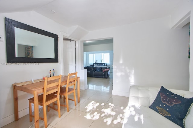 tiled dining space featuring vaulted ceiling