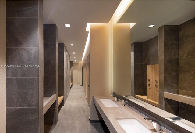 bathroom with tile flooring, tile walls, a tile shower, and double sink vanity