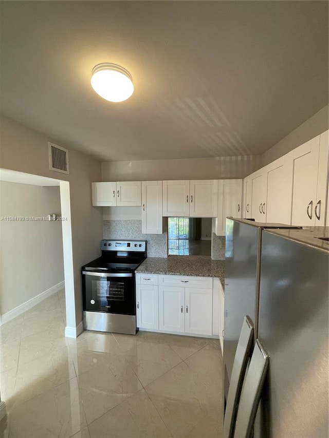 kitchen with decorative backsplash, stainless steel appliances, white cabinetry, and dark stone countertops