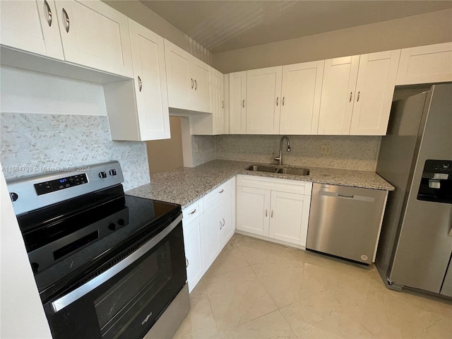 kitchen with light stone countertops, backsplash, stainless steel appliances, sink, and white cabinets