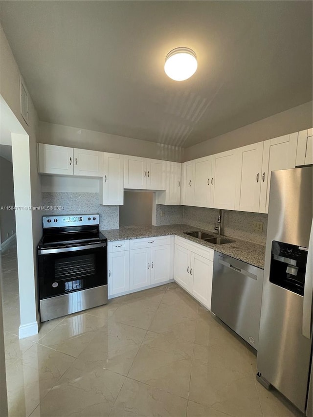 kitchen with stone counters, stainless steel appliances, white cabinetry, and sink