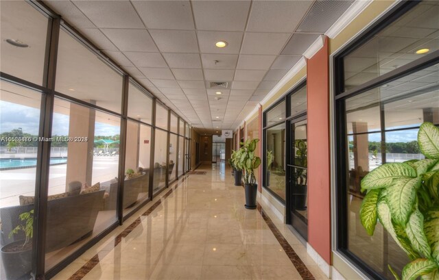 hall with crown molding, tile flooring, a healthy amount of sunlight, and a wall of windows