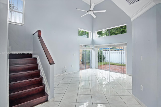 entryway featuring ceiling fan, light tile flooring, and a high ceiling