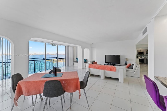 dining area with light tile flooring and a water view