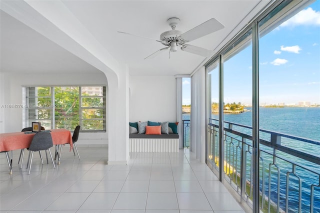 sunroom featuring ceiling fan and a water view