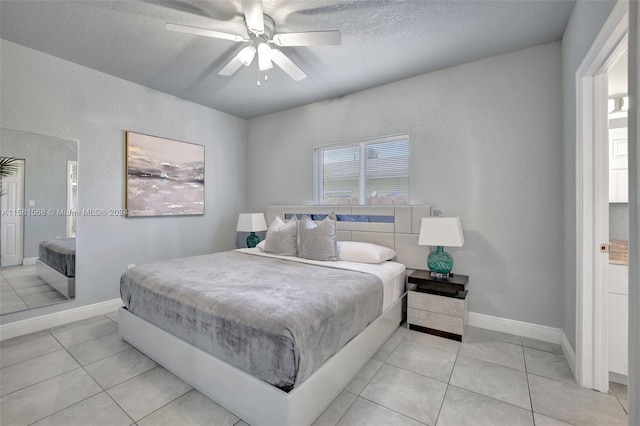 tiled bedroom with connected bathroom, ceiling fan, and a textured ceiling