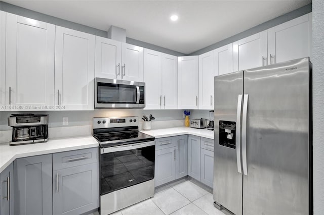 kitchen featuring gray cabinets, appliances with stainless steel finishes, white cabinets, and light tile flooring