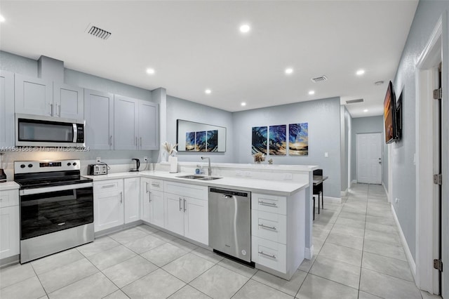 kitchen with sink, kitchen peninsula, stainless steel appliances, and light tile flooring