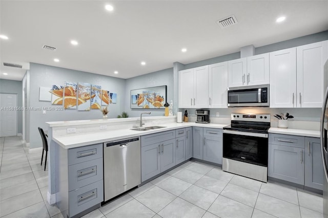 kitchen featuring appliances with stainless steel finishes, gray cabinets, sink, and light tile flooring