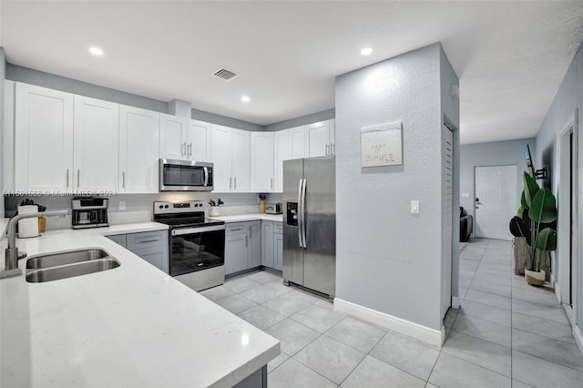 kitchen featuring sink, light tile flooring, white cabinetry, and stainless steel appliances