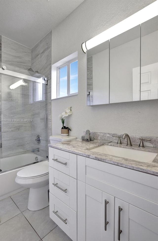 full bathroom featuring shower / bath combination with glass door, vanity, tile flooring, toilet, and a textured ceiling