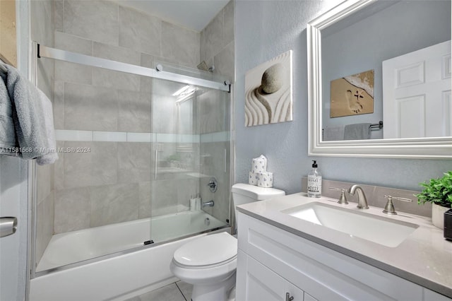 full bathroom with tile floors, vanity, toilet, and bath / shower combo with glass door