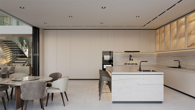 kitchen featuring sink, tasteful backsplash, a kitchen island, and black double oven