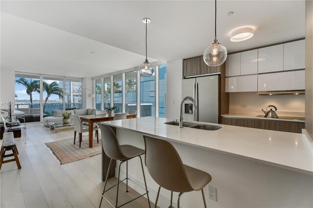 kitchen featuring white cabinets, decorative light fixtures, stainless steel fridge, and light hardwood / wood-style floors