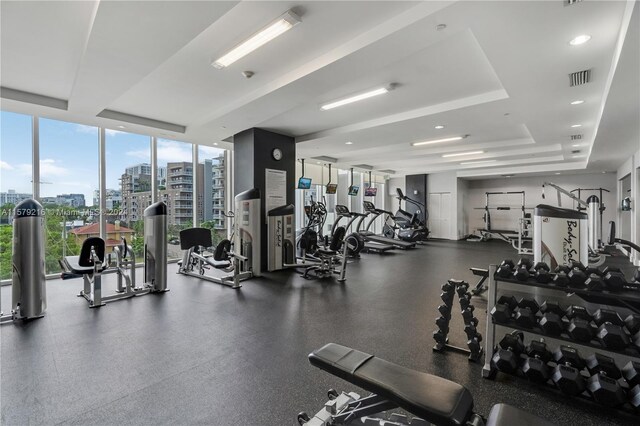 gym with a tray ceiling and expansive windows