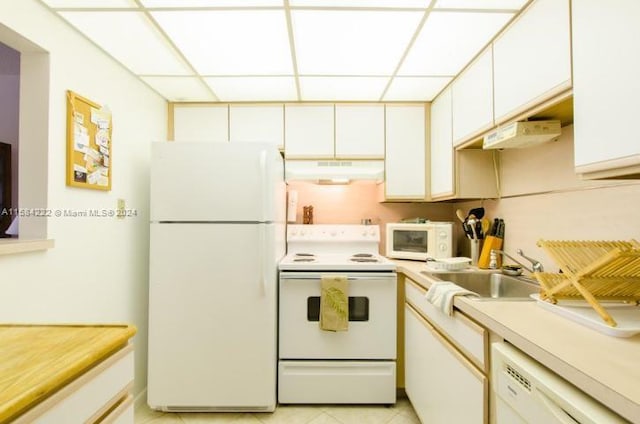 kitchen featuring light tile floors, white appliances, white cabinets, sink, and a paneled ceiling