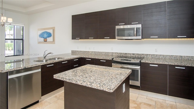 kitchen featuring appliances with stainless steel finishes, sink, a kitchen island, and light stone countertops