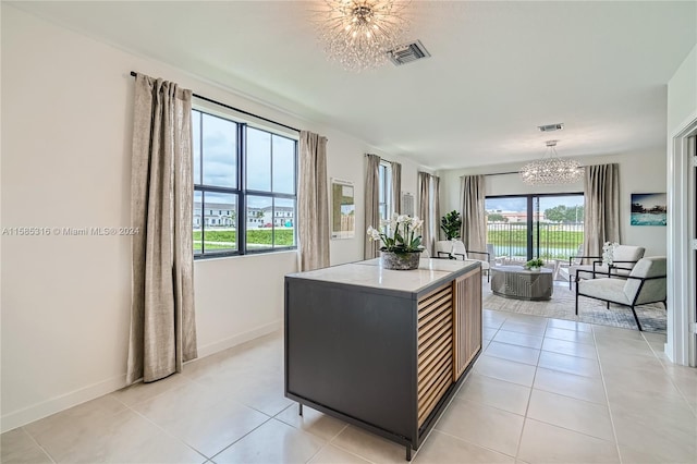 kitchen featuring light stone countertops, decorative light fixtures, a notable chandelier, a center island, and light tile floors