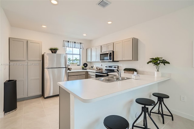 kitchen with a kitchen breakfast bar, stainless steel appliances, kitchen peninsula, and light tile floors