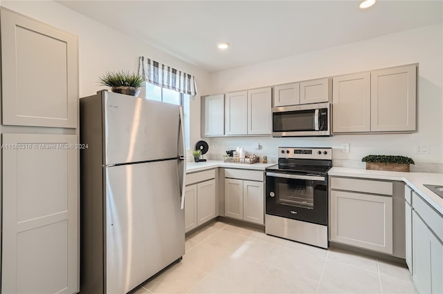 kitchen with light tile flooring, stainless steel appliances, and gray cabinets