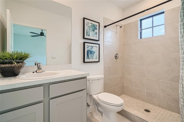 bathroom with ceiling fan, vanity, toilet, and a tile shower