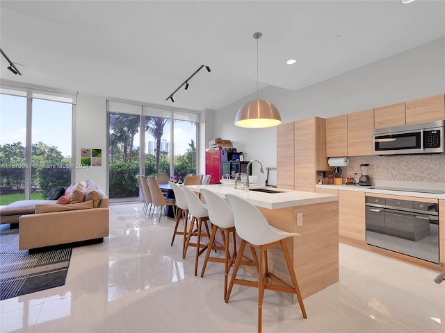 kitchen with oven, sink, tasteful backsplash, light tile flooring, and track lighting