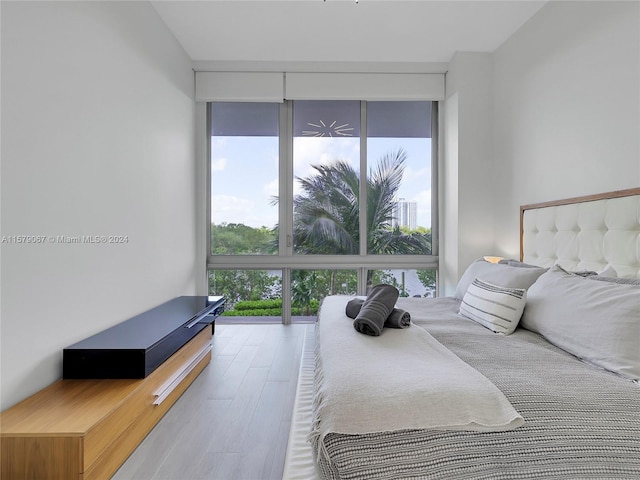 bedroom with hardwood / wood-style floors, a wall of windows, and multiple windows