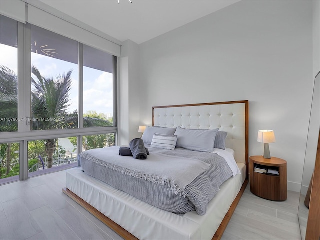 bedroom with floor to ceiling windows and light wood-type flooring