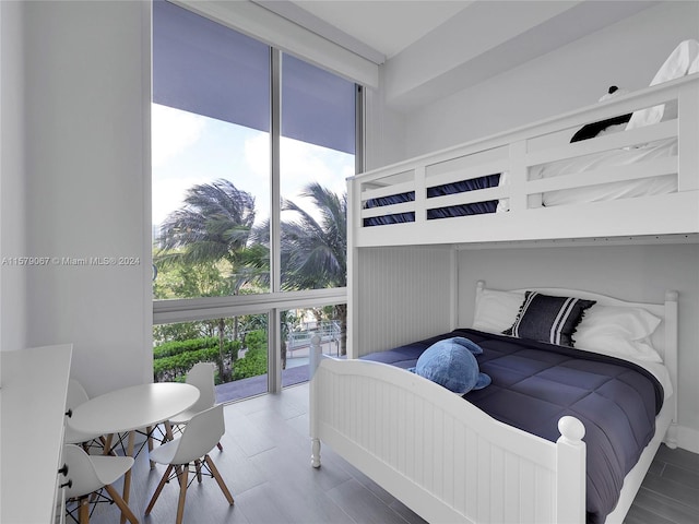 bedroom with wood-type flooring and a wall of windows