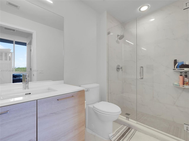 bathroom with a shower with door, vanity, and toilet