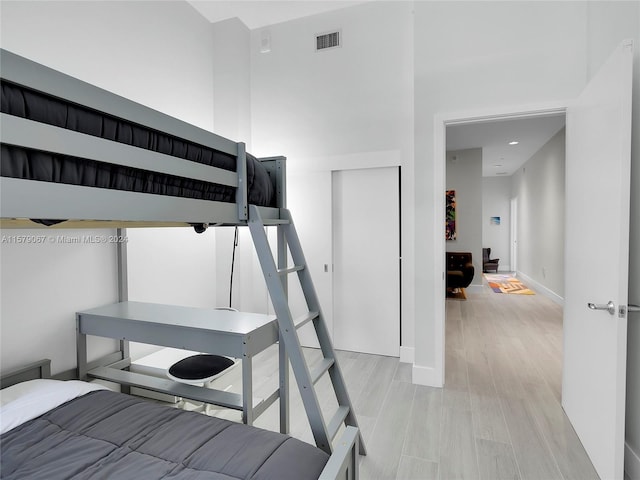 bedroom with light hardwood / wood-style flooring and a high ceiling