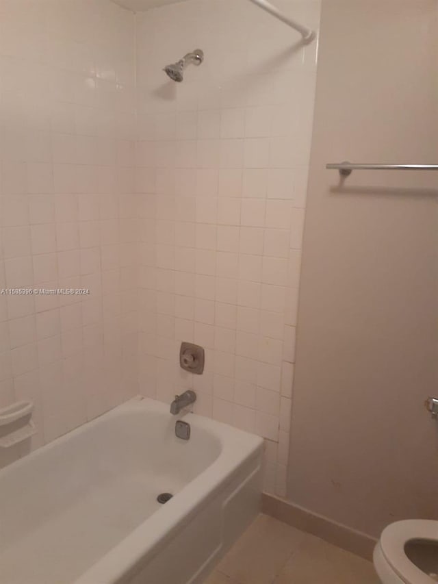 bathroom featuring tile flooring, tiled shower / bath combo, and toilet