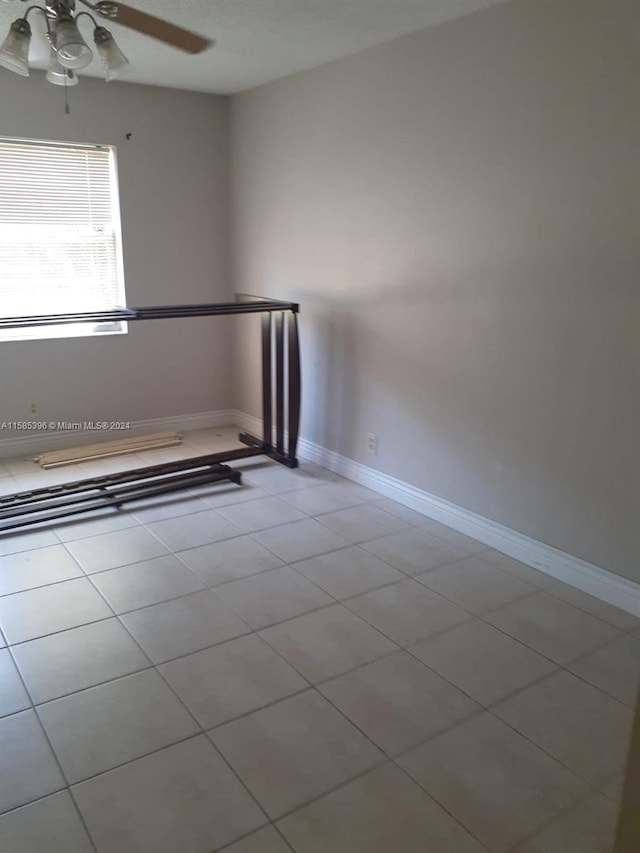 tiled empty room featuring ceiling fan