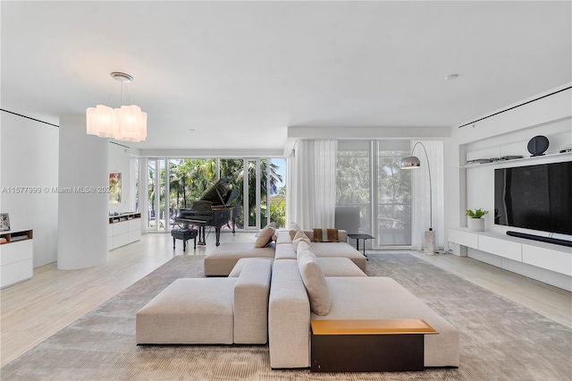 living room with hardwood / wood-style floors, floor to ceiling windows, a healthy amount of sunlight, and a notable chandelier