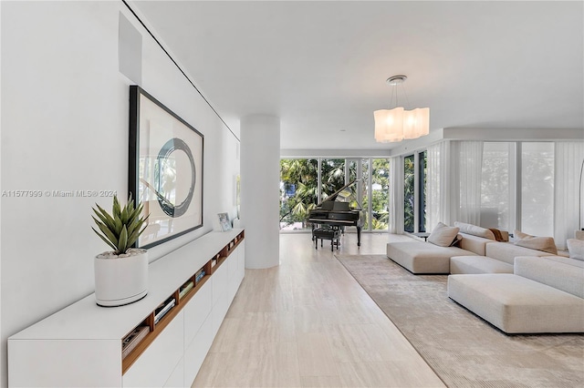 living room with light wood-type flooring, an inviting chandelier, and a wall of windows