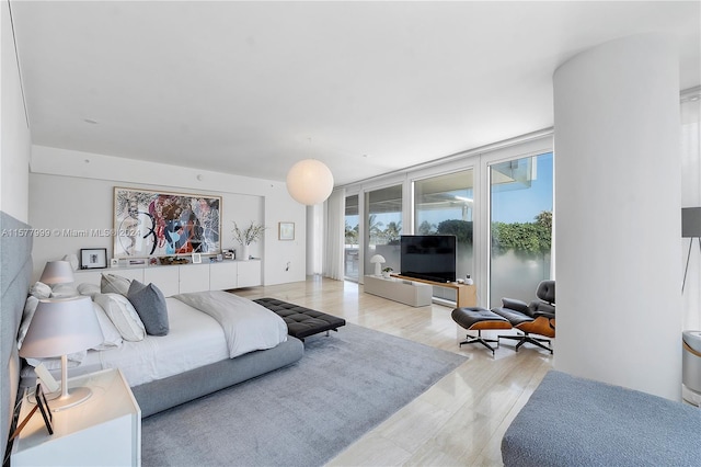 bedroom featuring access to outside, light hardwood / wood-style floors, and floor to ceiling windows